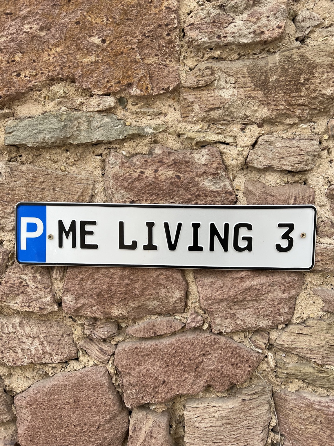 Parkplatzschild ME LIVING 3 an der Natursteinwand